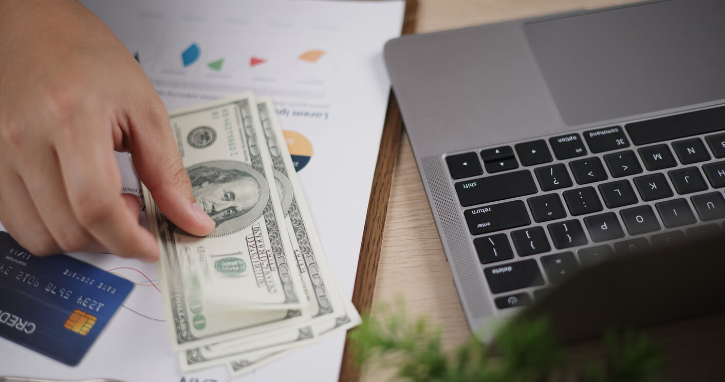 a desk with several items on it including a computer and money